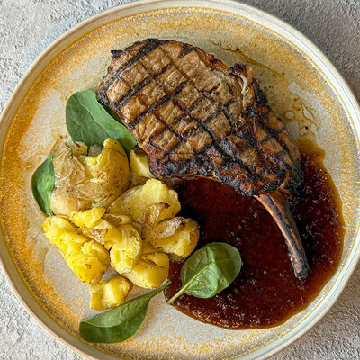 Стейк из свиной корейки Томагавк в мясной глазури с печеным картофелемв Терраса по цене 1230 ₽