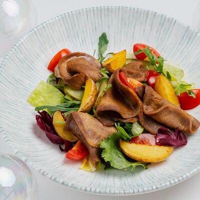 Теплый салат с языком, маринованными огурцами, картофелем и соусом сливочный хрен в ЛайкиПарк по цене 650 ₽