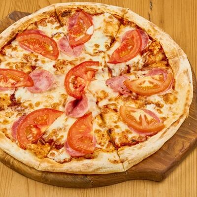 Пицца с ветчиной и томатами в 4 сыра по цене 910 ₽