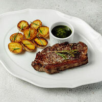 Стриплойн с печеным картофелем и соусом чимичурри в Bocconcino