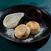 Сырники с изюмом, сметаной и брусничным соусом в Juno