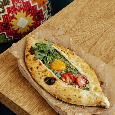 Хачапури по-аджарски с зеленью, сыром и картофелем в Бурка по цене 525 ₽