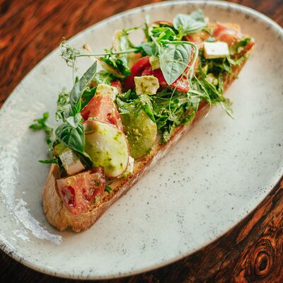 Брускетта с томатами и сербской брынзой в соусе песто в Макадамия по цене 490 ₽