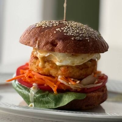 Бургер с котлетой из трески и форели, глазуньей, капустой и морковкой по-корейски, соусами горчичный и BBQ в Зерно по цене 620 ₽
