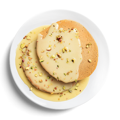 Банановые панкейки с соусом из белого шоколада и фисташками в Кухня на районе по цене 319 ₽