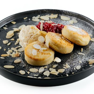 Сырники с кокосовым кремом и вишневым конфи в Комод по цене 400 ₽