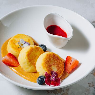 Сырники с кремом из вареной сгущенки и соусом из черной смородины в Casa di panna по цене 450 ₽