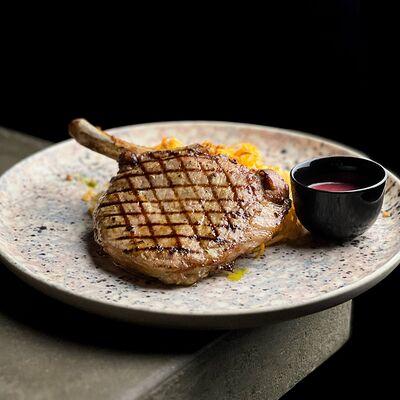 Свиная корейка на кости, тушеная капуста, брусничный соус в Нобель по цене 830 ₽