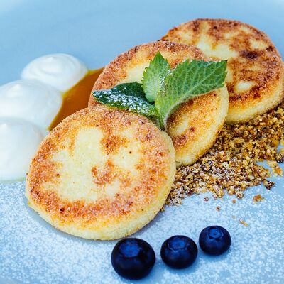 Сырники с пюре манго, сметаной и карамелизированным белым шоколадом в Bun по цене 450 ₽