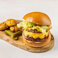 Бургер с двойной котлетой, жареным беконом, маринованным огурцом, красным луком и томатами в АндерСон