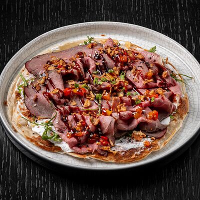 Слоеная лепешка роти с копченым ростбифом, кремом фета и луком-фрив Brasserie Lambic по цене 1160 ₽