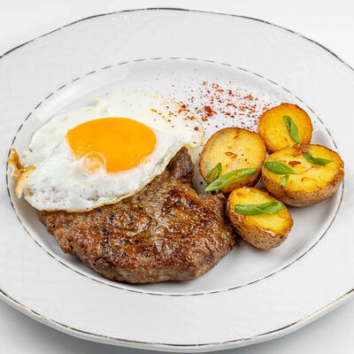 Свиная отбивная с яйцом, картофелем и дедовским салатом из огурца в Мамино по цене 770 ₽