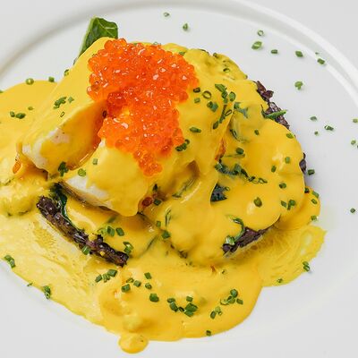 Запеченный палтус счерным ризотто, шафрановым соусом и красной икрой в Romano по цене 2900 ₽